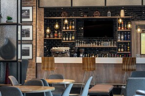 A bar area with a brick wall, shelves with bottles, and a TV screen. - Park Inn by Radisson Serviced Apartments, Lagos Victoria Island (Lagos)