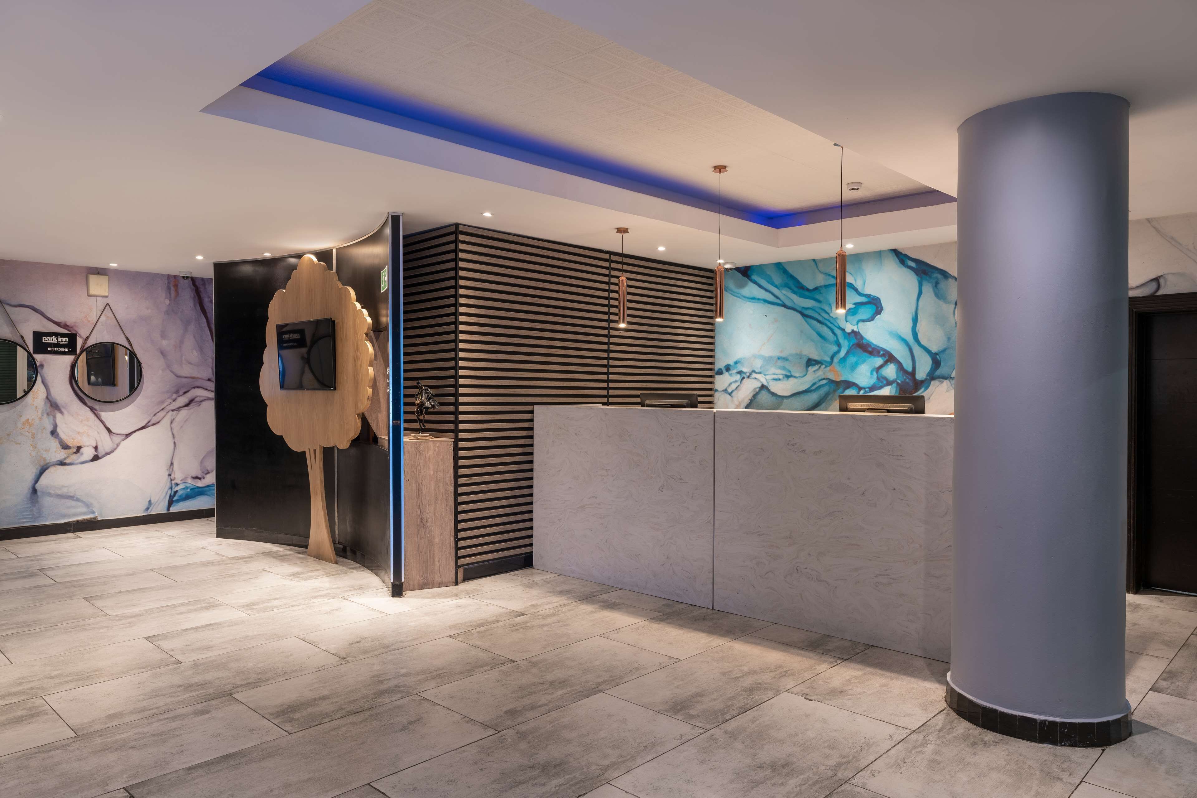 Una zona de recepción moderna con piso de mármol, un mostrador de recepción y una columna grande.