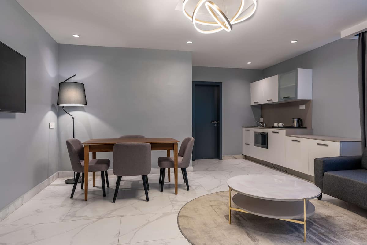 A modern, well-lit living room with a dining area, a kitchen, and a seating area.
