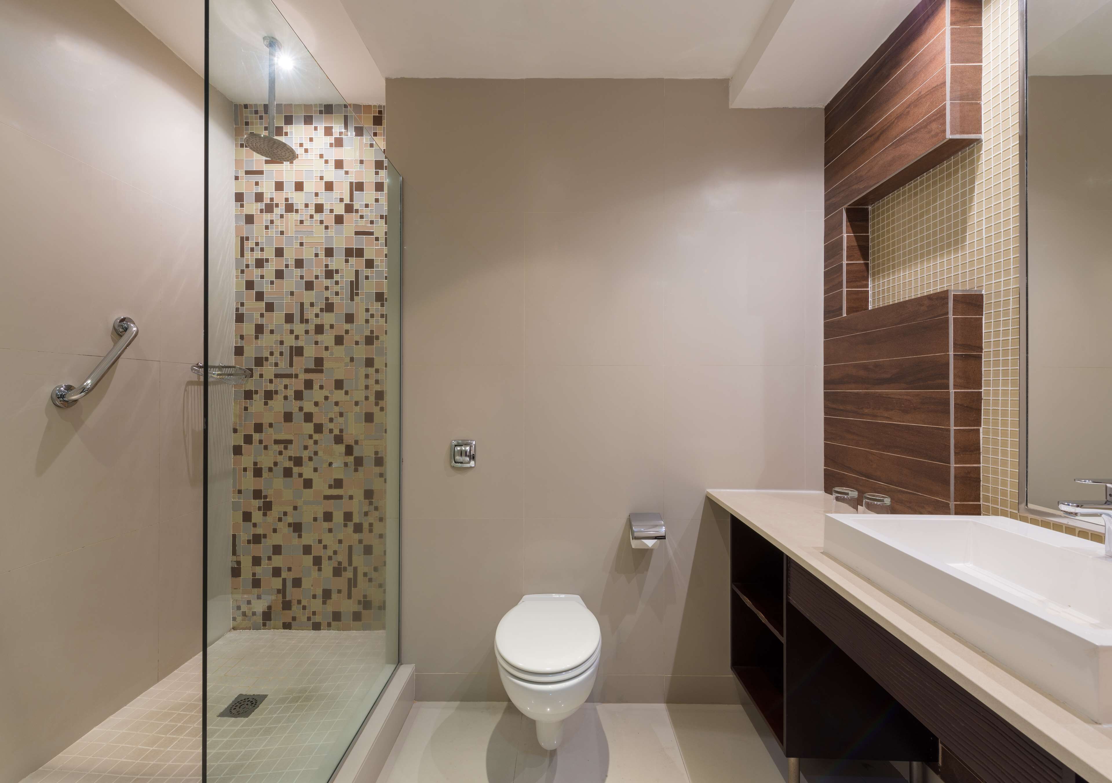 Ein modernes Badezimmer mit einer gläsernen Duschkabine, einer weißen Toilette und einem großzügigen Waschbecken mit Holzschrank.