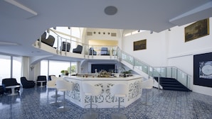 A spacious, modern interior with a central bar area, multiple seating options, and a staircase leading to an upper level.