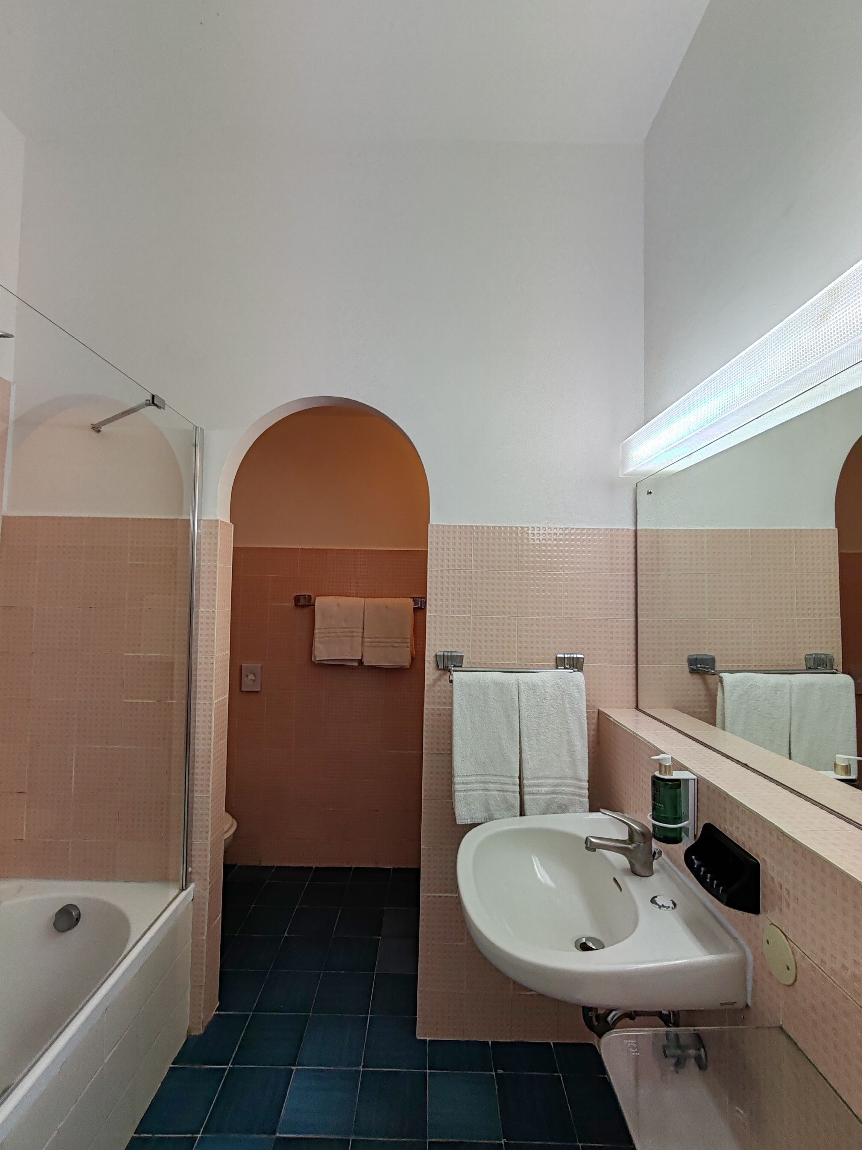 A bathroom with a bathtub, sink, and mirror.