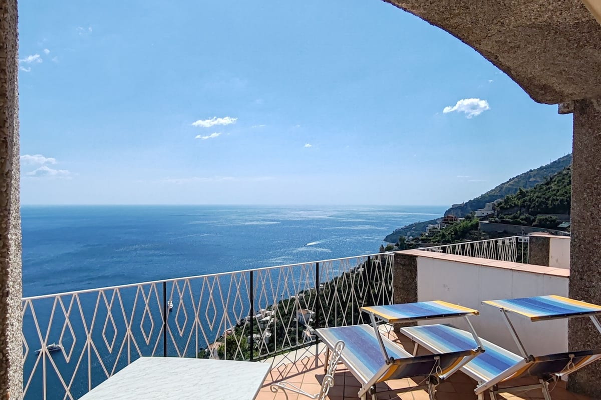 Una terraza con mesa y sillas, vista al mar y suelo de baldosas.