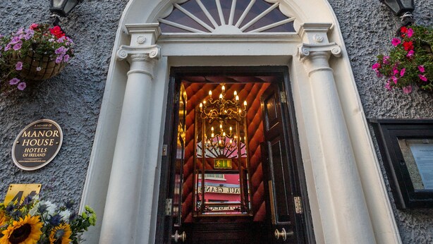 The entrance of Benners Hotel with a classic facade, a sign above the door, and flower baskets on either side. - Dingle Benners Hotel (Dingle)