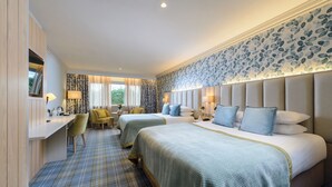 A hotel room with two beds, a desk, a chair, and a patterned carpet. - Dingle Benners Hotel (Dingle)
