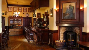 A traditional interior with a bar area, wooden furniture, a fireplace, and various framed pictures on the walls. - Dingle Benners Hotel (Dingle)