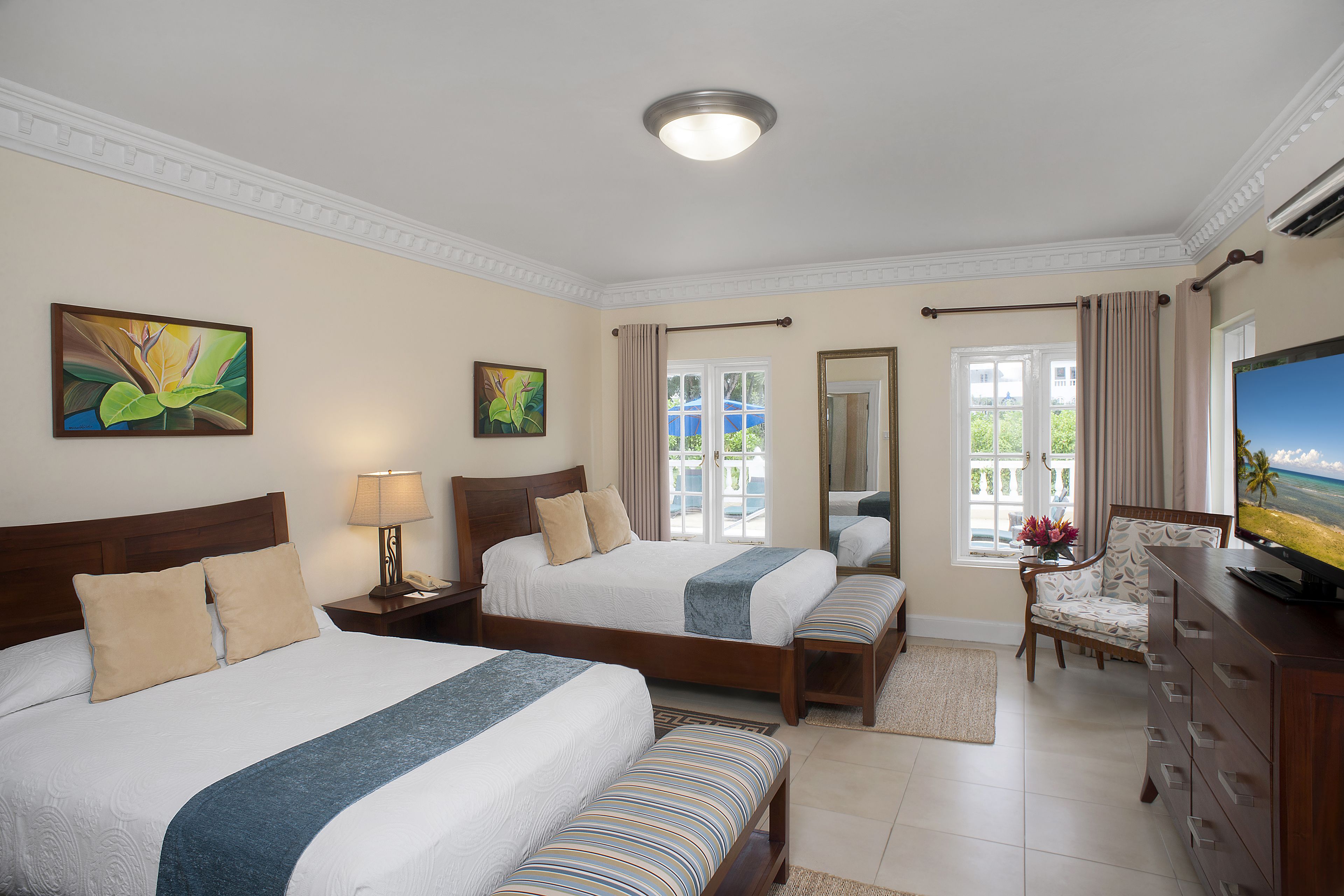 A hotel room with two beds, a TV, a chair, and a view of the outdoors.