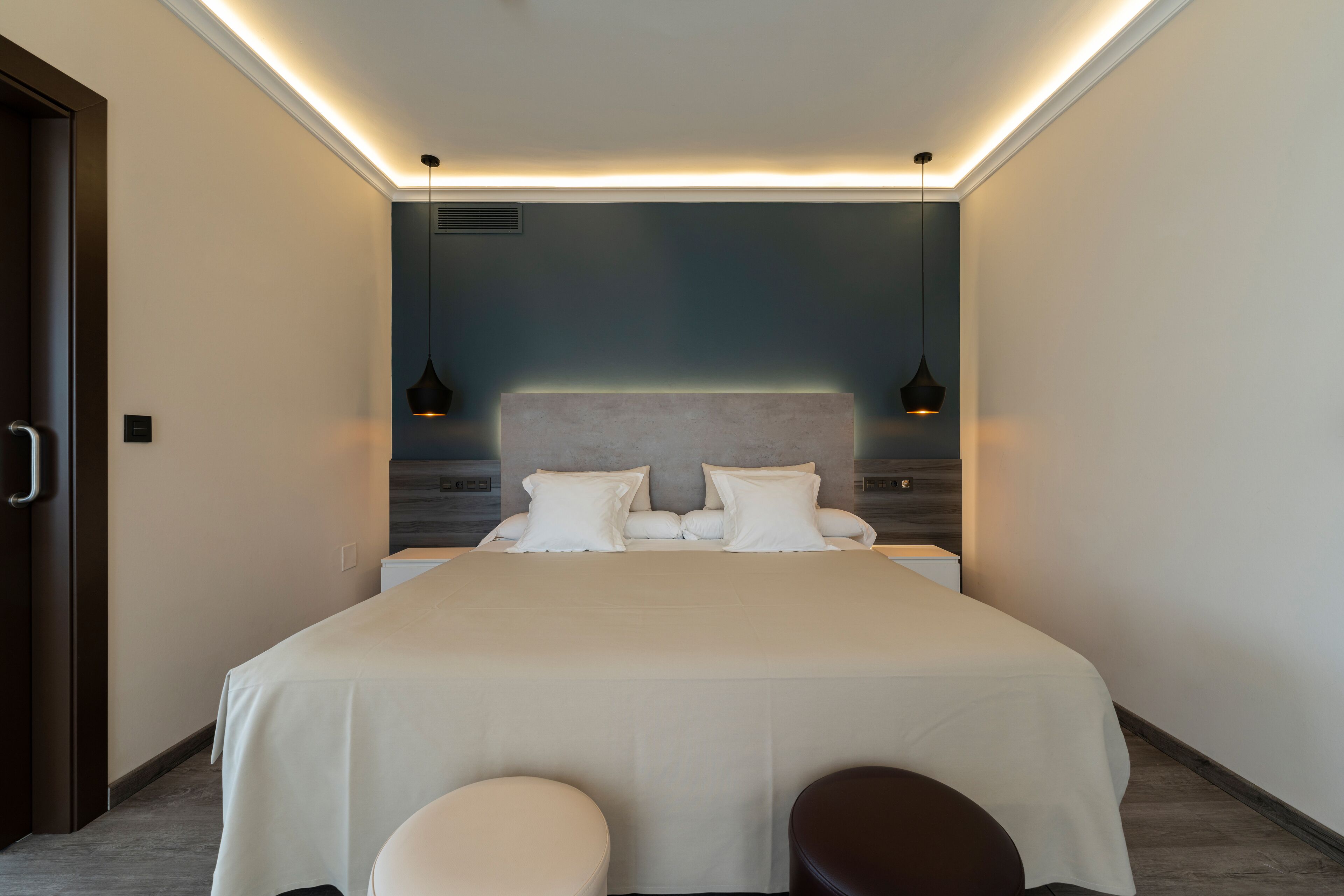 A modern bedroom with a large bed, two bedside tables, and a headboard.