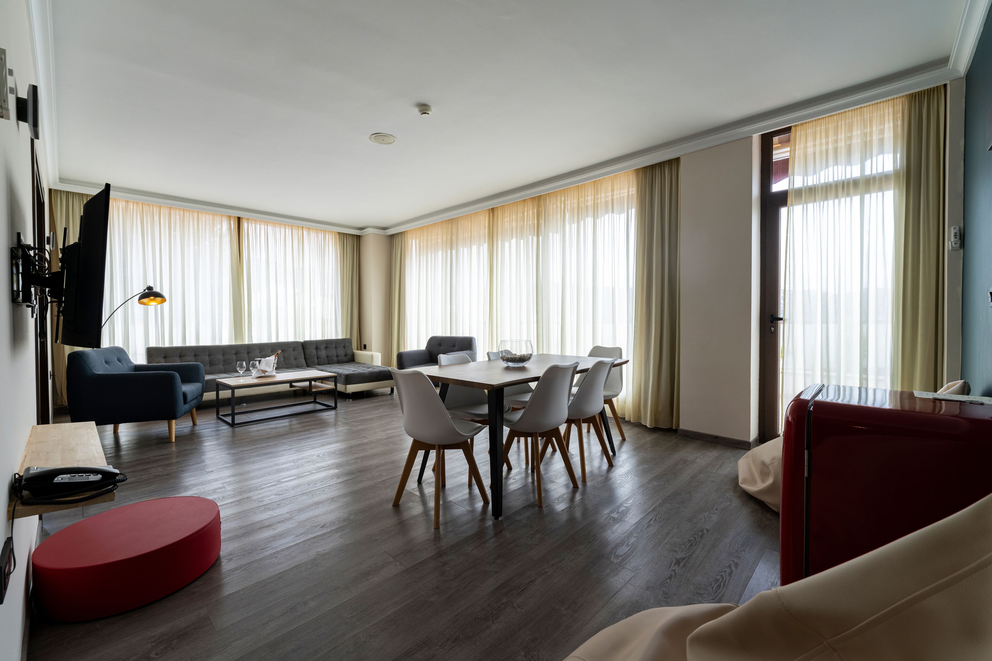 A modern living room with a dining area, featuring a sofa, a coffee table, and a dining table with chairs.