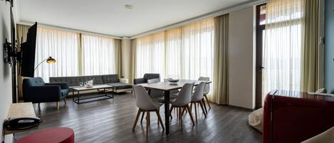 A modern living room with a dining area, featuring a sofa, a coffee table, and a dining table with chairs.