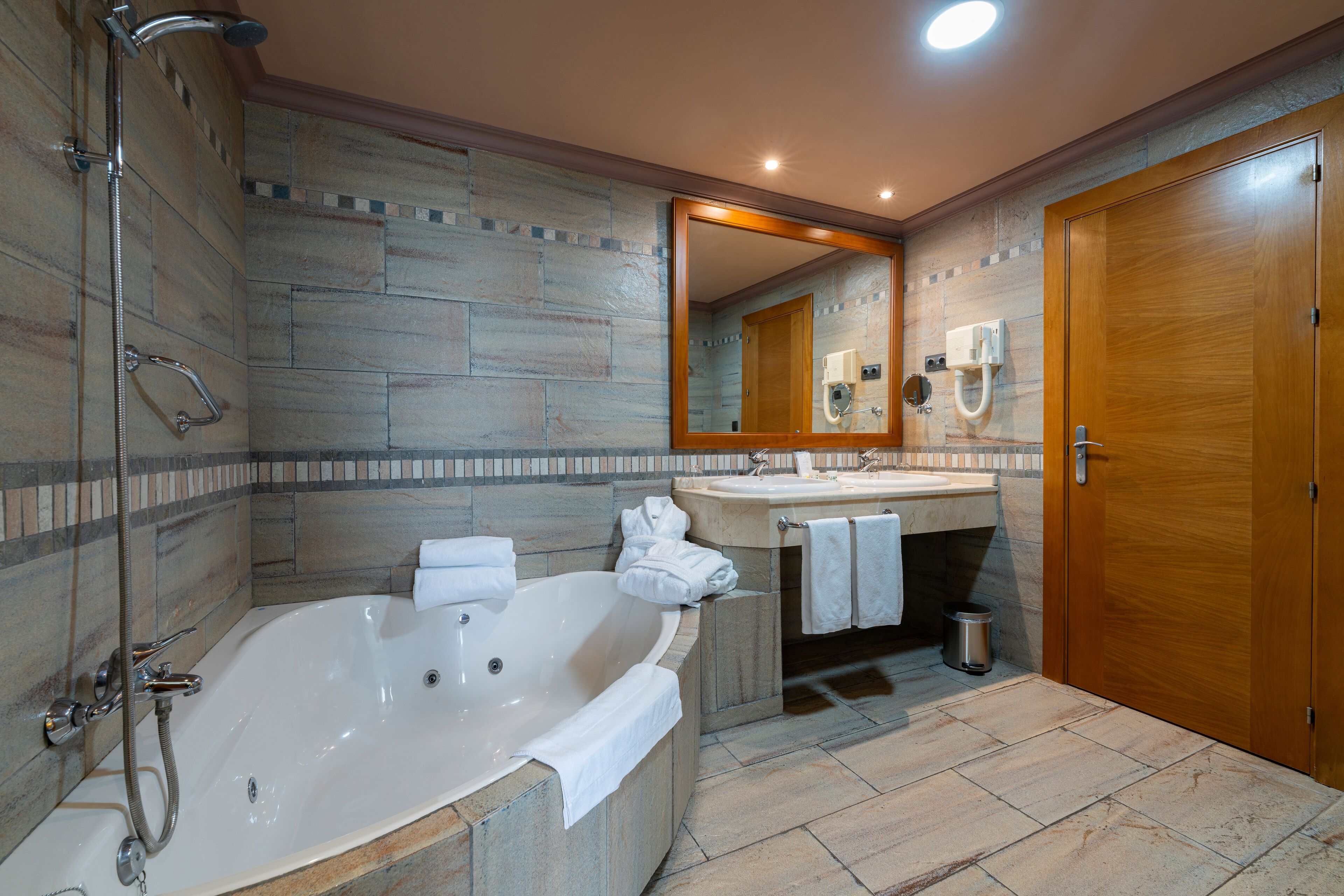 Un baño con una bañera grande, un lavamanos, un espejo y una ducha.