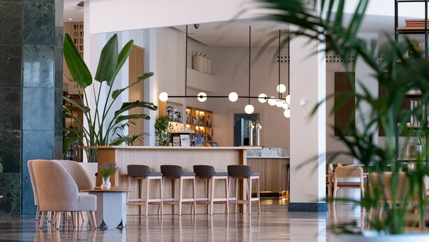 Eine moderne Bar mit einer Marmorsäule, Barhocker und Pendelleuchten.