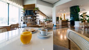 Eine moderne Hotelhalle mit Essbereich, Treppe und Rezeption.