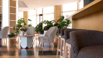 Un lobby moderno con asientos, plantas y un suelo pulido.