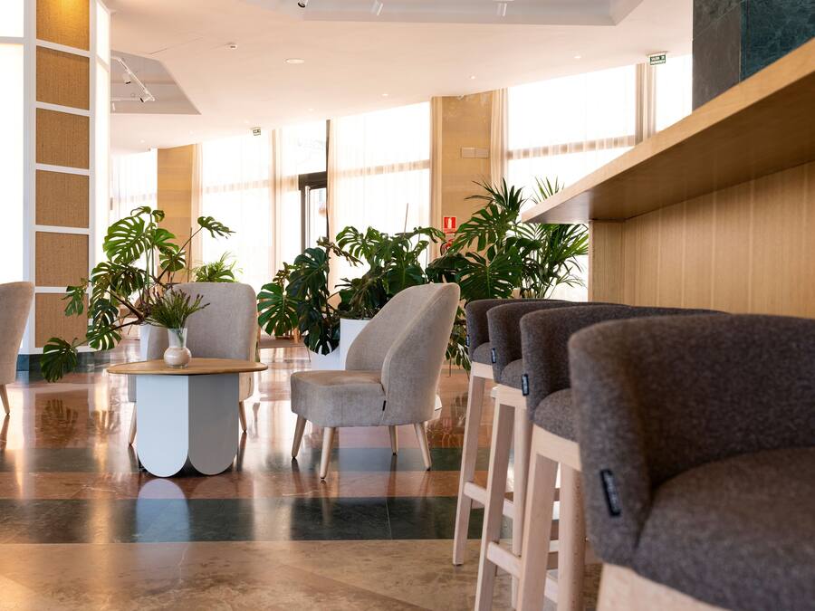 Un lobby moderno con asientos, plantas y un suelo pulido.