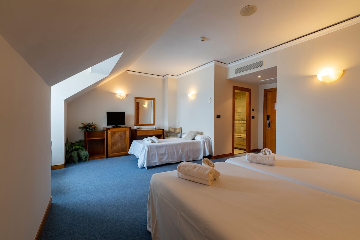 A hotel room with two beds, a desk, a television, and a mirror.