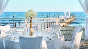 A table set for a wedding with a view of the ocean and a pier. - Elias Beach Hotel (Limassol)