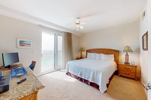 A hotel room with a bed, a desk with a computer, a TV, and a balcony with a view. - Celadon Beach Resort (Panama City Beach)