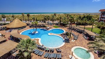 A resort with a large central pool, multiple smaller pools, and a beach view.