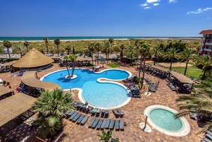 Resort com uma piscina central ampla, várias piscinas menores e vista para a praia.