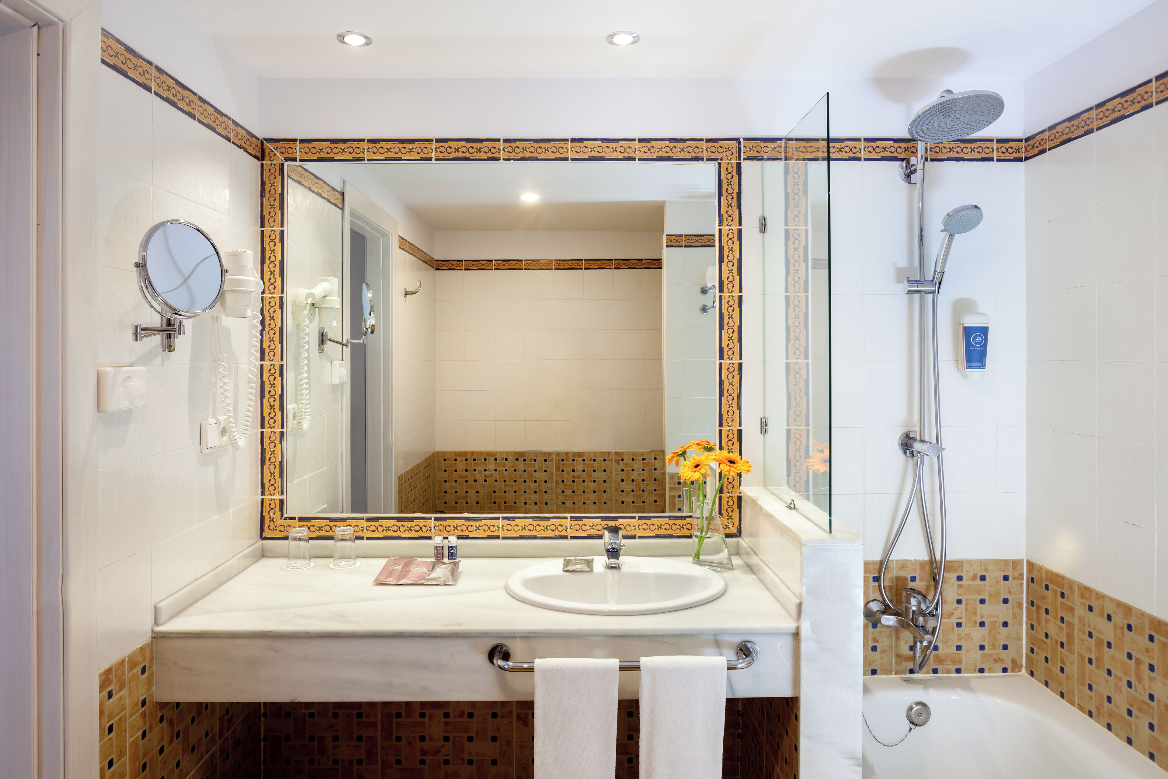 A bathroom with a sink, mirror, and shower.