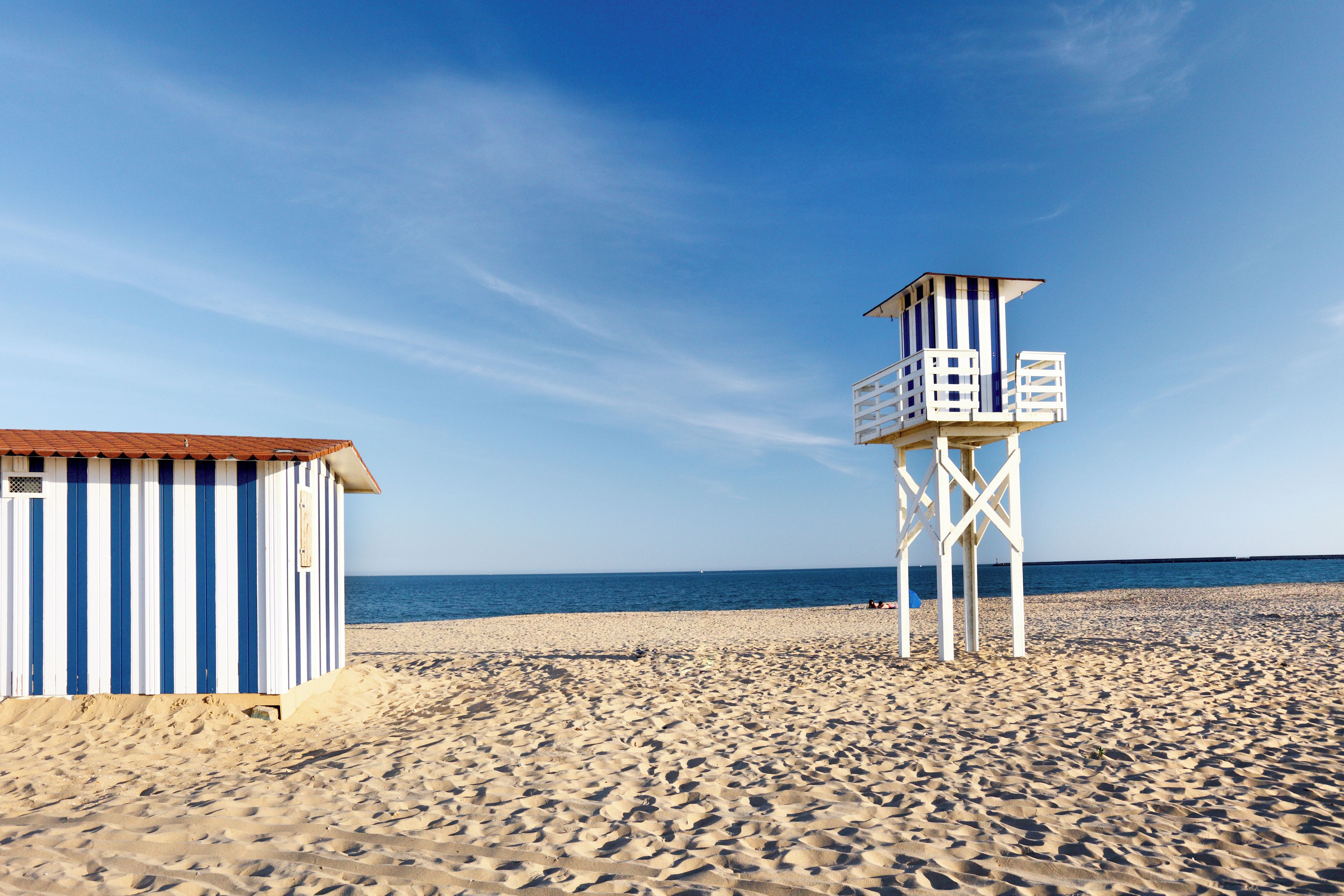 Une plage avec une tour de surveillance pour les sauveteurs et un bâtiment à rayures.