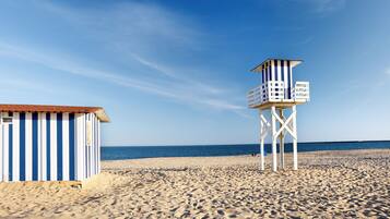 Une plage avec une tour de surveillance pour les sauveteurs et un bâtiment à rayures.