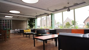 A modern interior with seating areas, large windows, and a brick wall. - The Budget Hotel (Hazerswoude-Rijndijk)