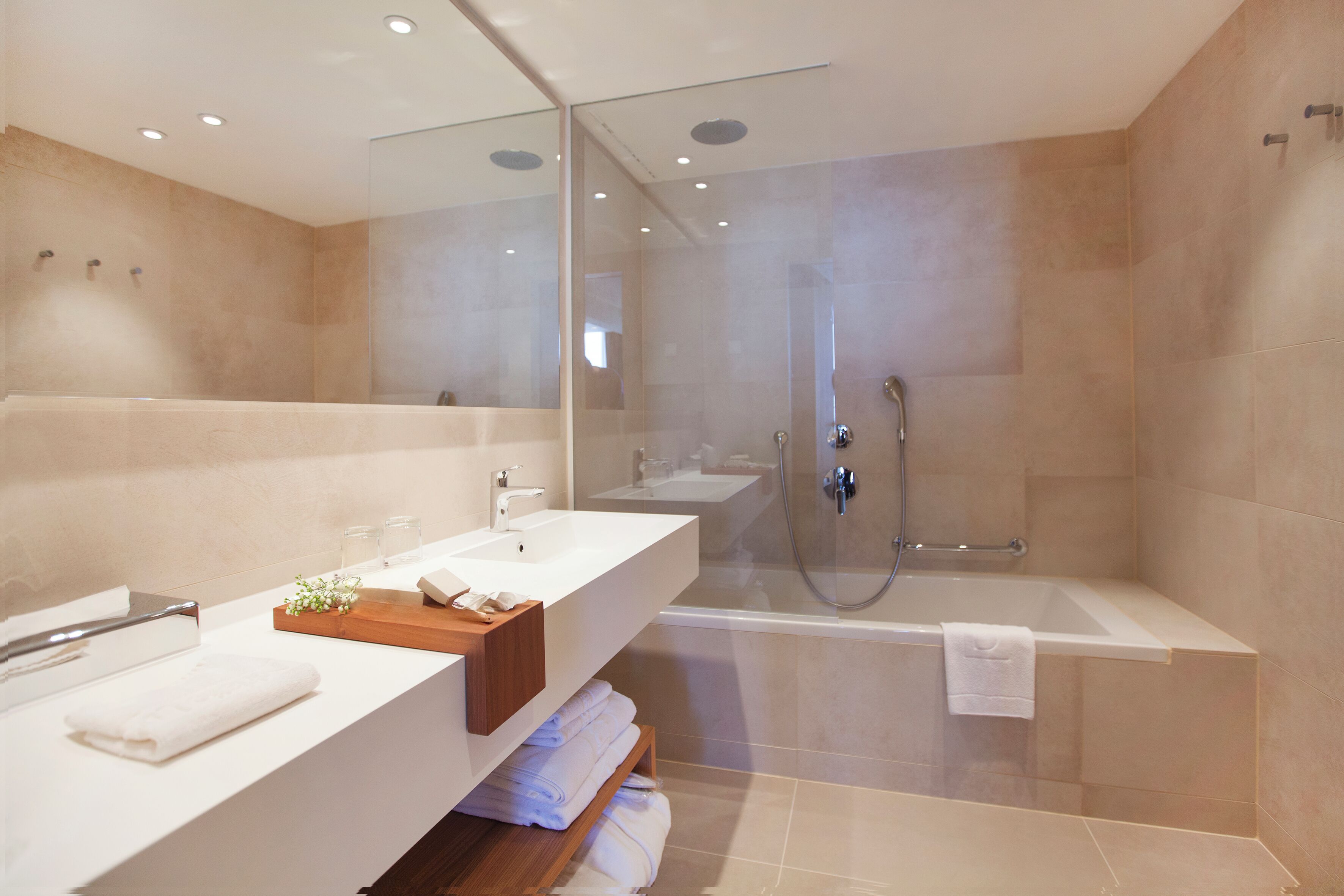 Un baño moderno con ducha de vidrio, una bañera grande y un tocador con espejo.