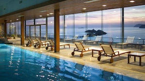 Una piscina interior con sillones de descanso y vistas al mar.