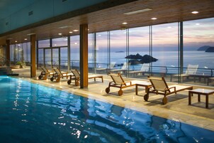 Una piscina techada, una piscina al aire libre de temporada, sombrillas