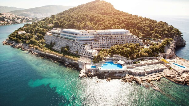 Un hotel costero con varias edificaciones, una piscina y un litoral rocoso.