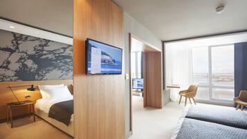 A modern hotel room with a bed, bedside table, TV, and a large window.