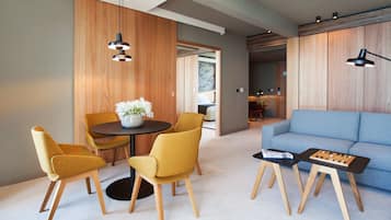 Uma sala de estar moderna com um sofá azul, painéis de parede em madeira e um espaço de jantar com cadeiras amarelas e uma mesa redonda.