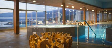 A wooden sculpture in a lobby with a pool and large windows overlooking a body of water.