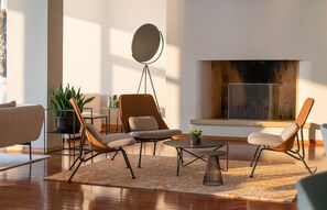 A modern living room with a fireplace, a round coffee table, and two armchairs.