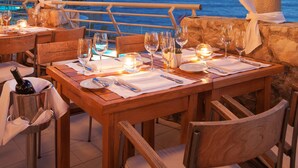 Un área de comedor al aire libre con mesas dispuestas para una comida, con vista al mar.