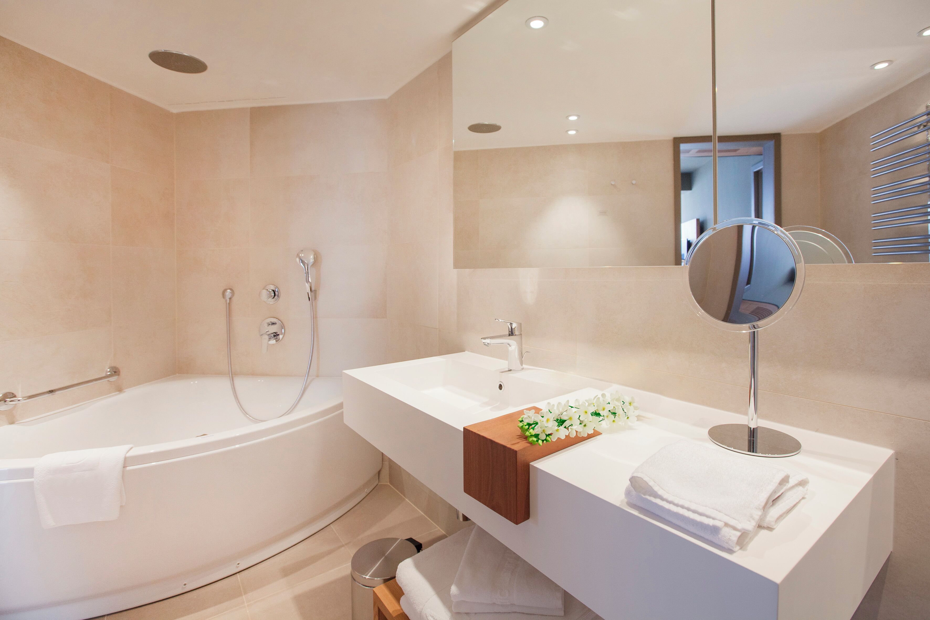 A modern bathroom with a bathtub, a vanity with a mirror, and a sink.