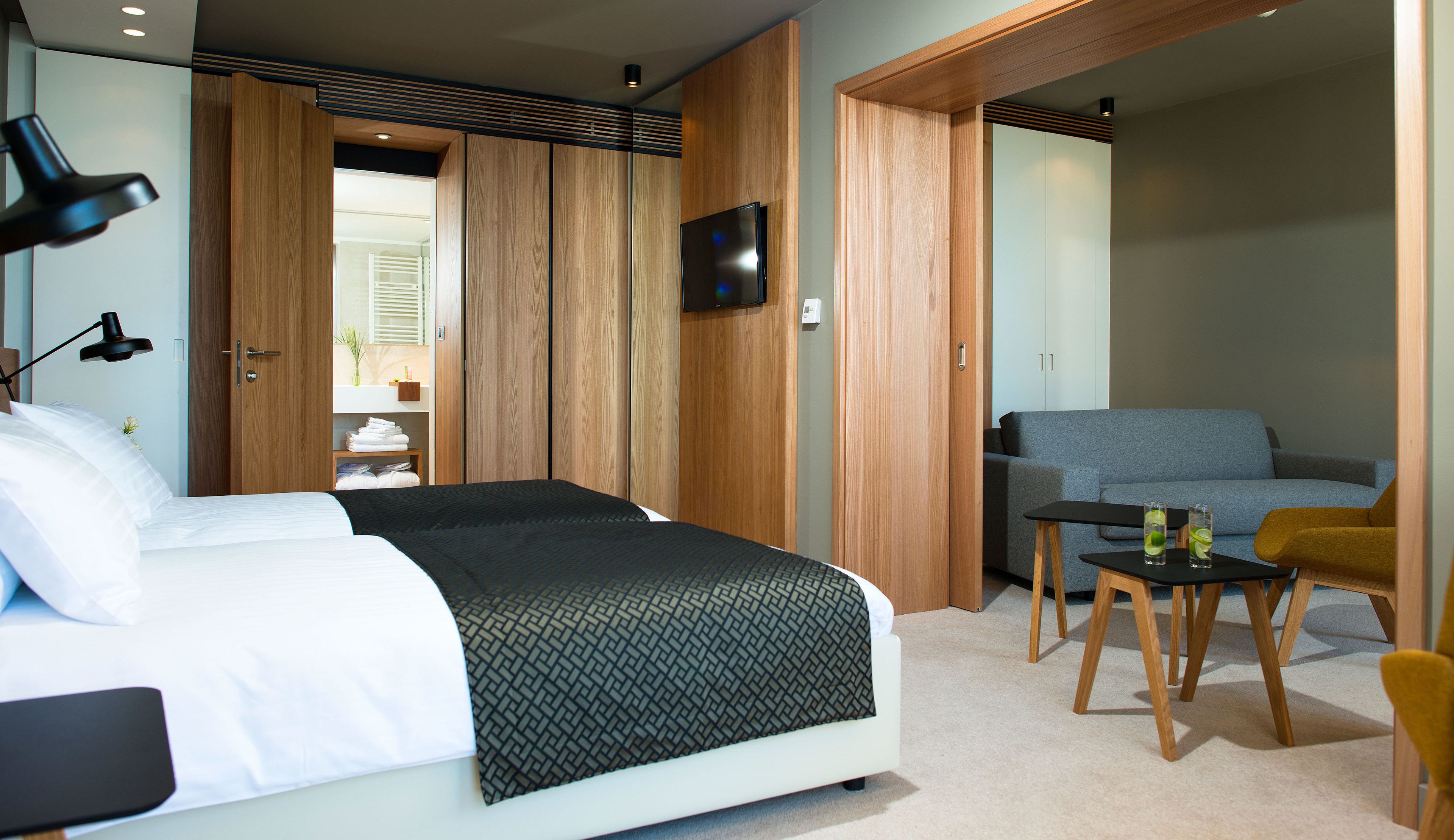 Ein Hotelzimmer mit Bett, Schreibtisch, Stuhl, Fernseher und einer Couch.