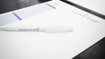 A table with a white notepad, a pen, and a bouquet of flowers.