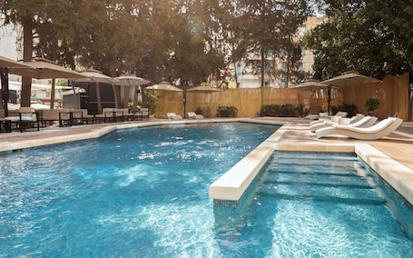 Una piscina al aire libre, sillones reclinables de piscina