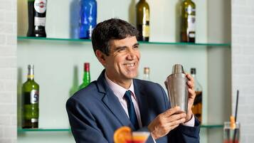 Un espace bar avec des étagères remplies de bouteilles d’alcool, un comptoir et un shaker à cocktails.