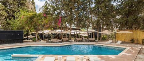 Una piscina al aire libre, sillones reclinables de piscina