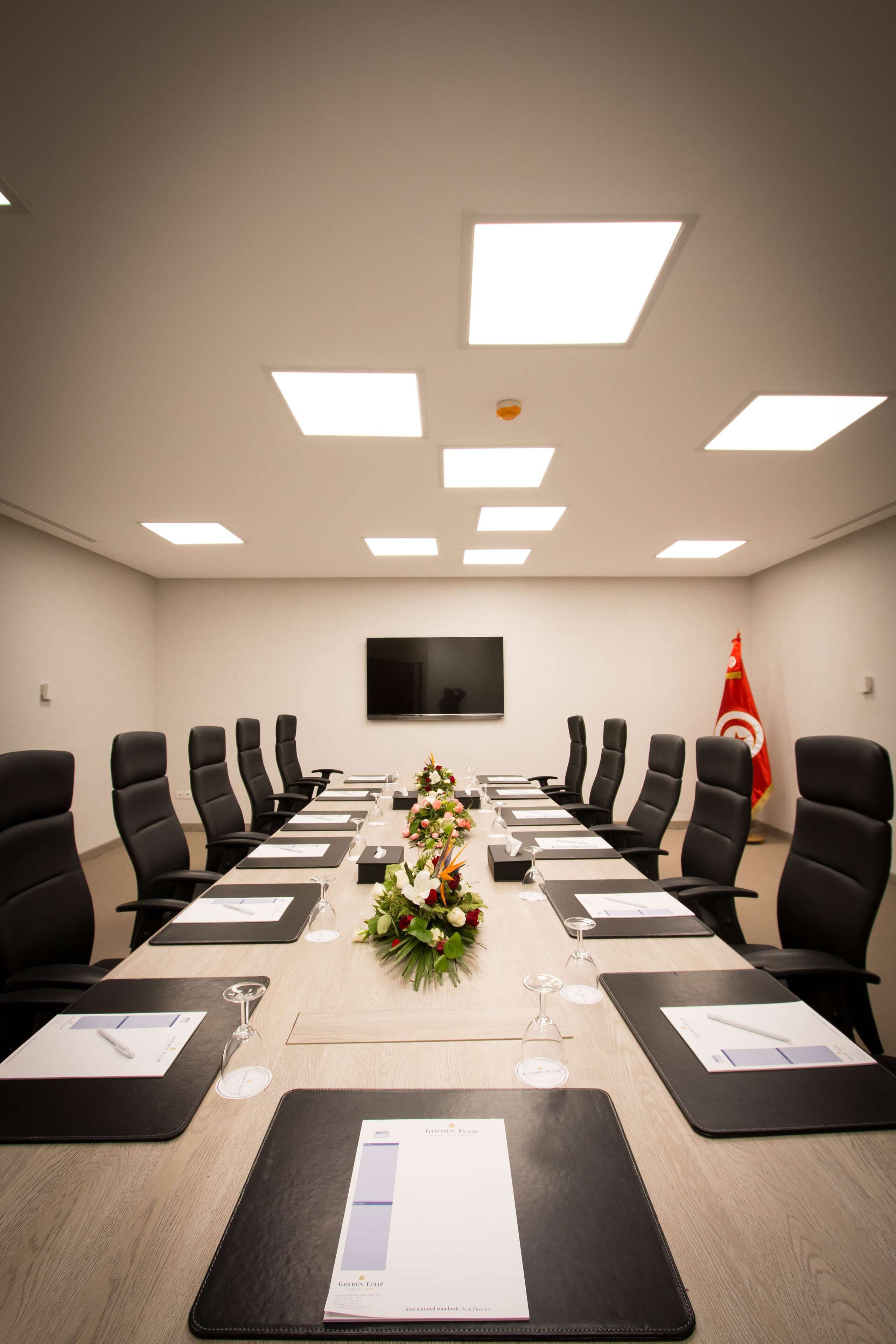A conference room with a long table, black chairs, and a flag.