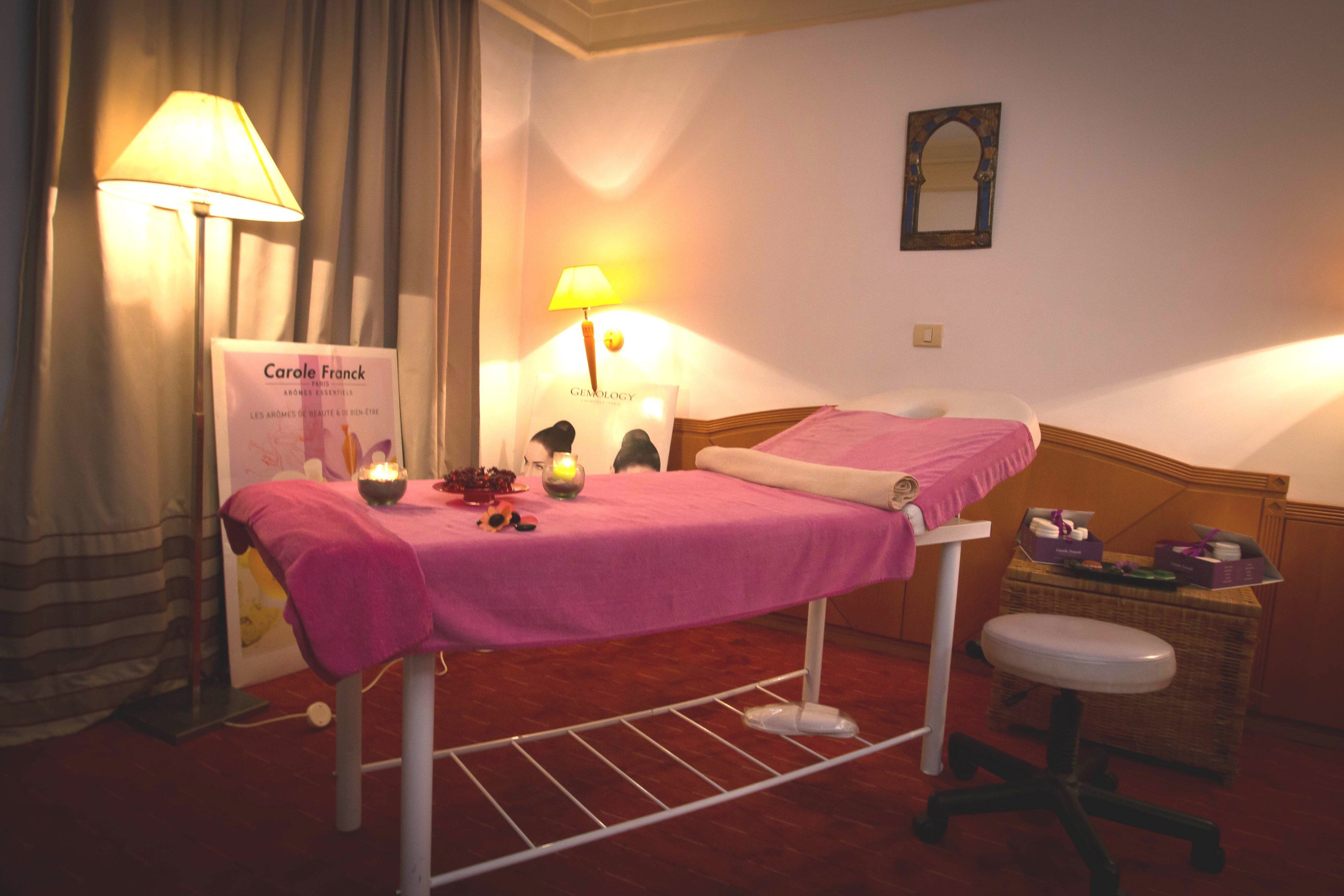 Una habitación de hotel con una cama, una mesita con velas, una silla y un cartel de Carole Franck.