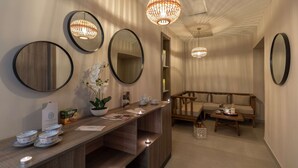 Un pasillo con espejos redondos, un banco de madera y una mesa con teteras y una orquídea en maceta.