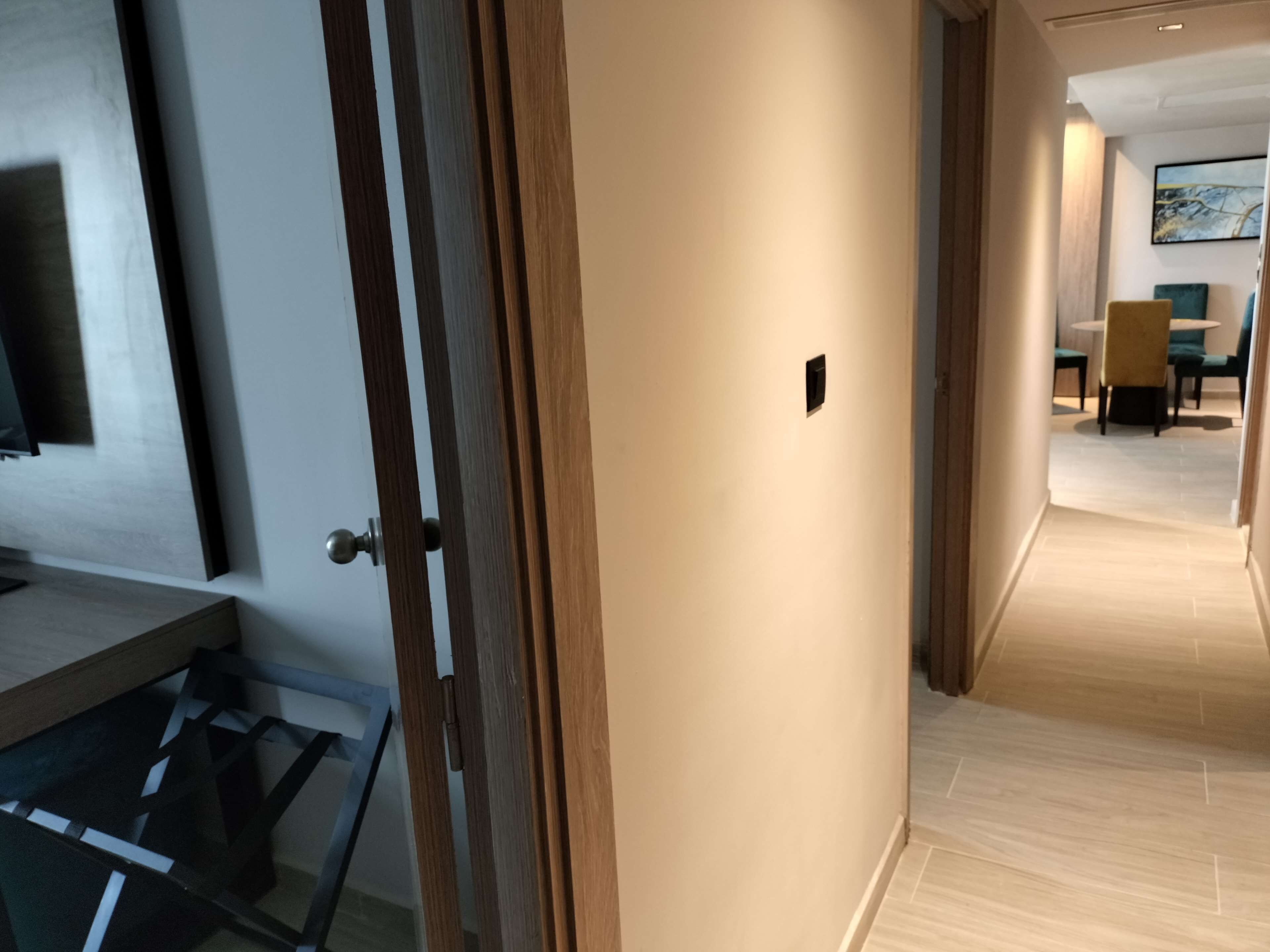 Un intérieur moderne avec une porte en bois, une vitrine et un coin repas comprenant des chaises et une table.