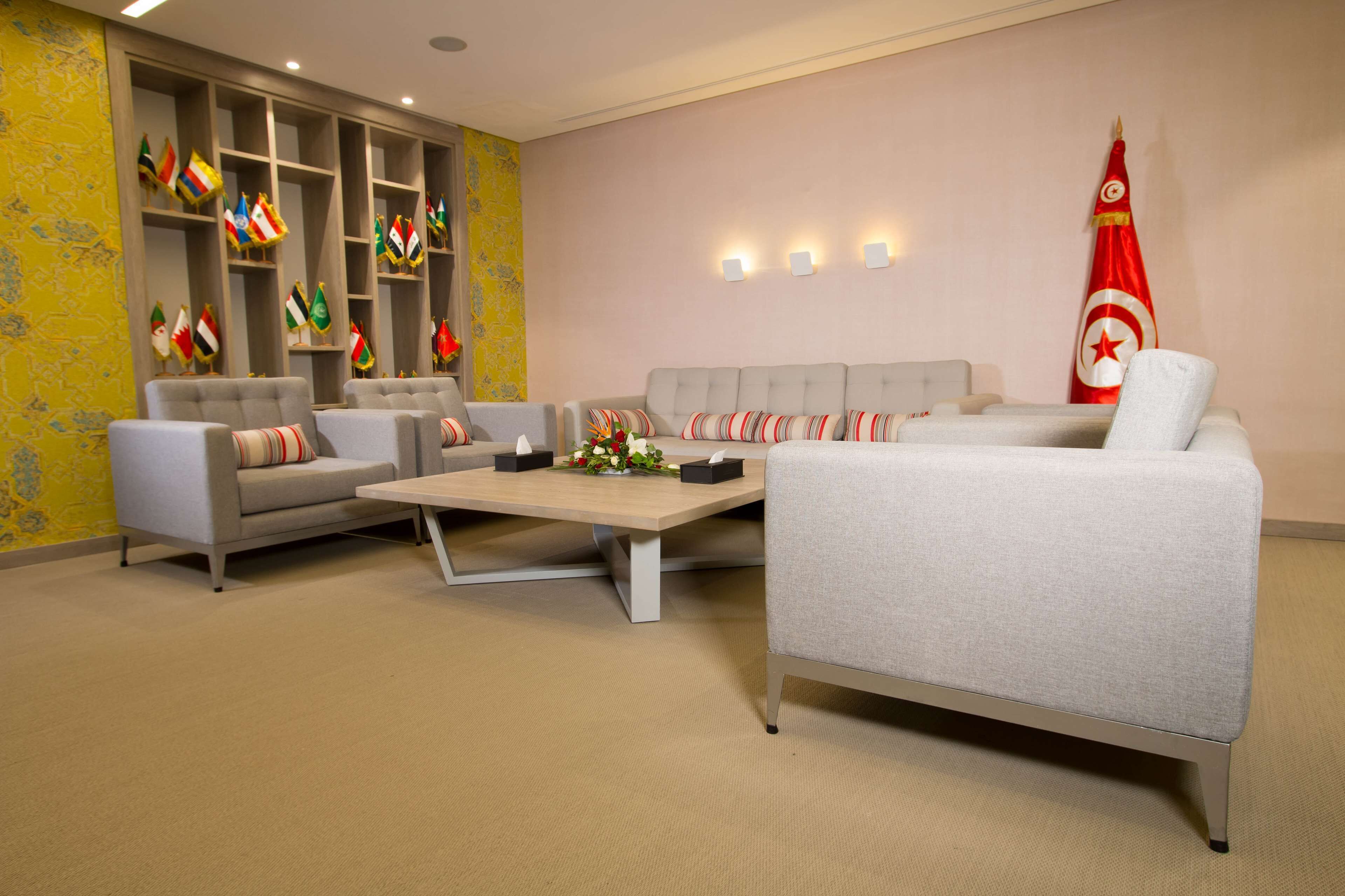 Een moderne loungehoek met banken, een bijzettafeltje en een verzameling nationale vlaggen.