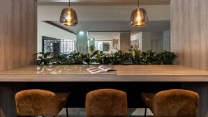 Una cocina moderna con encimera de madera, tres sillas tapizadas e iluminación colgante.