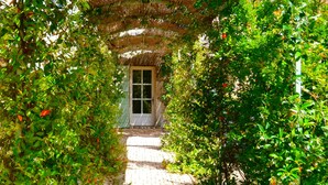 Un sendero en un jardín que lleva a una puerta bajo un tejado de paja.
